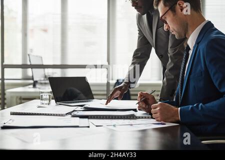 Side view of two businessmen discussing contract at table during meeting in office, copy space Stock Photo