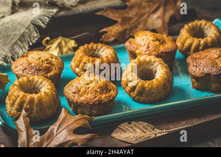 Homemade delicious mini bundt cakes, guglhupf, muffins on a blue plate on rustic wooden background with autumn decoration Stock Photo