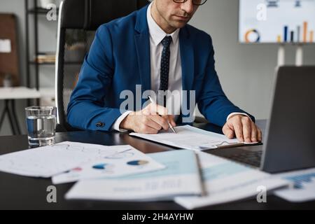 Close up of successful businessman in suit working at able in office and signing documents, copy space Stock Photo