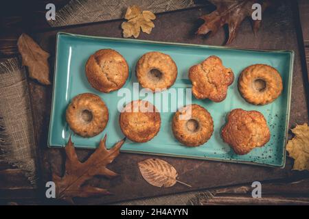 Homemade delicious mini bundt cakes, guglhupf, muffins on a blue plate on rustic wooden background, top view Stock Photo