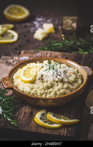 Lemon rice risotto with rosemary on dark wooden background, vertical Stock Photo