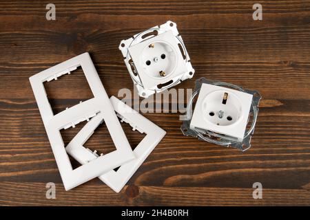 Electrical socket with decorative plastic parts on a wooden background. Stock Photo