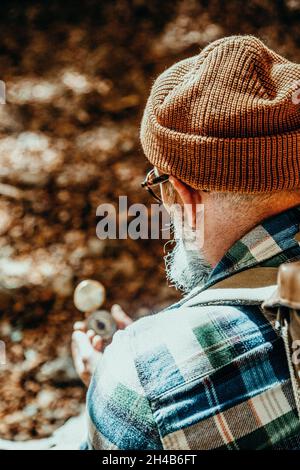 Rear view of an adventurous man consults his manual compass on a sunset excursion Stock Photo