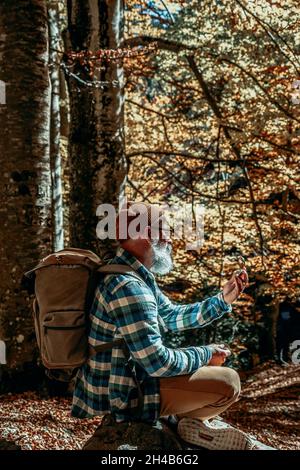 adventurous bearded man consults his manual compass on a sunset excursion Stock Photo