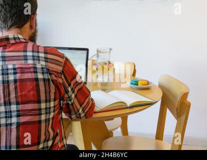 Rear view of man working on his laptop in the table with food Stock Photo