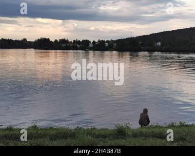 A worried man sitting in front of a lake. Mirroring from water. Stock Photo