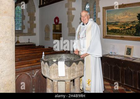 Anglican vicar by baptism font in local parish church, St John the Baptist Church, Sutton, West Sussex, England, United Kingdom Stock Photo