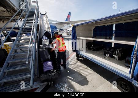 Los Angeles, California, USA. 29th Mar, 2019. An ground crew member loads gate checked bags onto a Delta Air Lines Inc. baggage cart on the tarmac at Los Angeles International Airport (LAX) on Friday, March 29, 2019 in Los Angeles, Calif. © 2019 Patrick T. Fallon (Credit Image: © Patrick Fallon/ZUMA Press Wire) Stock Photo