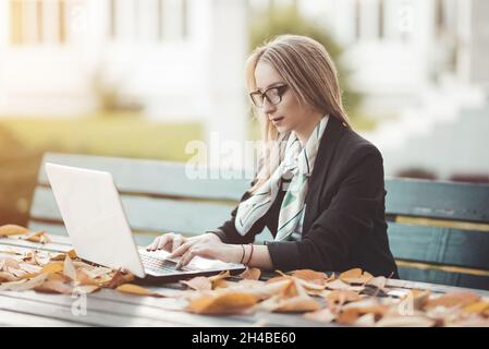 Beautiful young business woman working on laptop computer outside Stock Photo