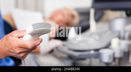 Male doctor holding ultrasonic probe in hand, ultrasound machine and patient ready for diagnostic Stock Photo