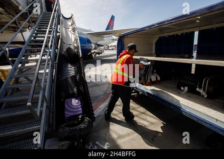 Los Angeles, California, USA. 29th Mar, 2019. An ground crew member loads gate checked bags onto a Delta Air Lines Inc. baggage cart on the tarmac at Los Angeles International Airport (LAX) on Friday, March 29, 2019 in Los Angeles, Calif. © 2019 Patrick T. Fallon (Credit Image: © Patrick Fallon/ZUMA Press Wire) Stock Photo