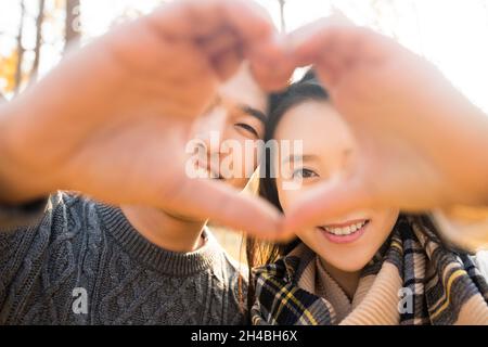 Happy young lovers making heart gesture Stock Photo