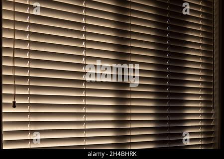 Office blinds, dark inside with sun peaking through from outdoors Stock Photo