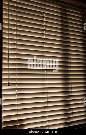 Office blinds, dark inside with sun peaking through from outdoors Stock Photo