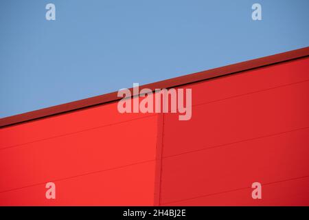 Helsinki / Finland - NOVEMBER 1, 2021: Closeup of red metallic building wall against bright blue sky during the sunset. Stock Photo