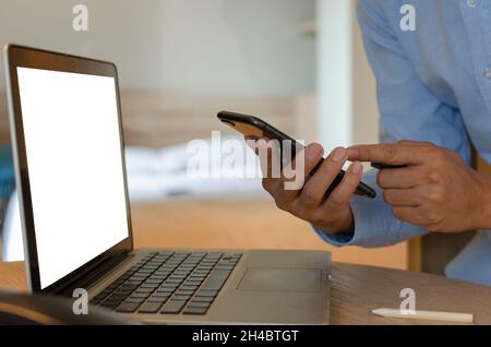 man using mobile smart phone and computer laptop on desk Stock Photo