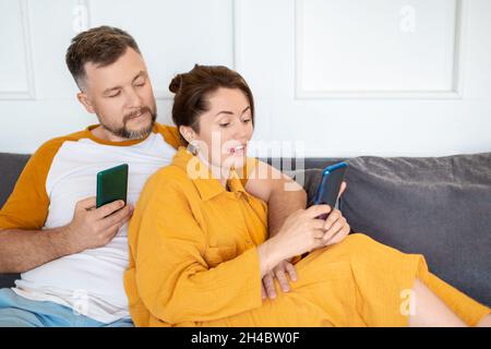 Photo of a middle aged couple with smartphones. Concept of modern technologies in everyday life. Stock Photo