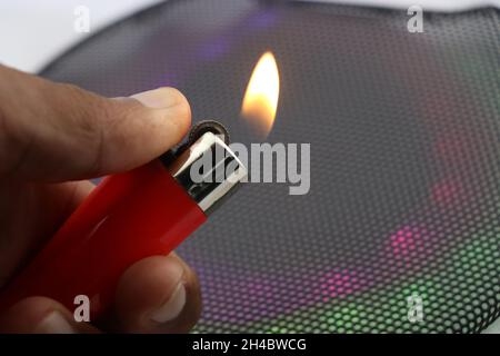 Lighter with fire held in hand with colorful dull lights on a background showing party and celebrations concept Stock Photo