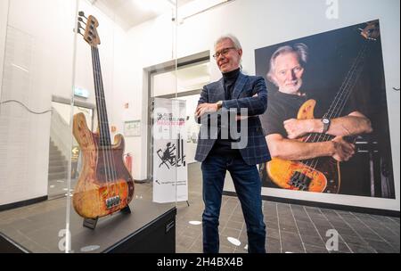 11 October 2021, Lower Saxony, Lüneburg: Carsten Junge, director of the Kunsthalle der Sparkassenstiftung Lüneburg, stands next to a bass guitar by Klaus Voormann in the exhibition. Klaus Voormann is considered the fifth Beatle, he met the Beatles in 1960 in the Kaiserkeller on St. Pauli. In the Kultur Bäckerei Lüneburg an exhibition is dedicated to his life's work for the first time. (to dpa 'Klaus Voormann - no one was as close to the Beatles') Photo: Philipp Schulze/dpa Stock Photo