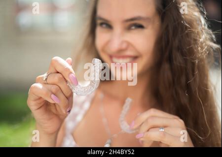 Beautiful caucasian woman holding transparent mouth guards for bite correction. Stock Photo