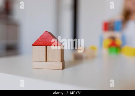 Child girl playing with colorful wooden toy building blocks. Little kid building tower or house at home or day care. Construction block for baby or to Stock Photo