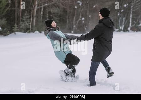 Happy couple of teenagers dancing and having fun in winter forest Stock Photo