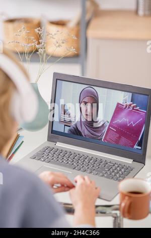 Young Muslim female on lapto poscreen showing financial document and explaining graph during online course of study Stock Photo