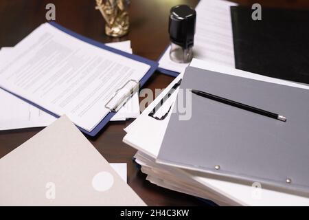 Part of table with stacks of juridical and business documents in folders and clipboards with pencil on top Stock Photo