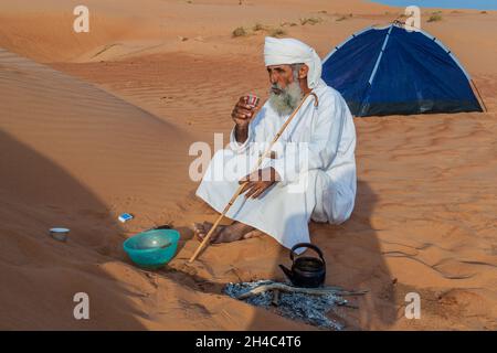 AL WASIL, OMAN - MARCH 6, 2017: Local bedouin prepares a coffee in the sand dunes of Sharqiya Wahiba Sands near Al Wasil village. Stock Photo