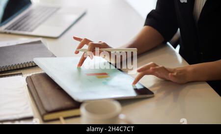 Cropped image of Businesswoman using tablet, fingers tapping, touching on a modern digital tablet screen to work on data report. Stock Photo