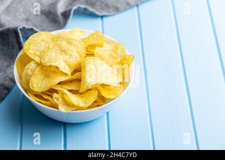 Crunchy potato chips. Potato crisps on blue table. Stock Photo
