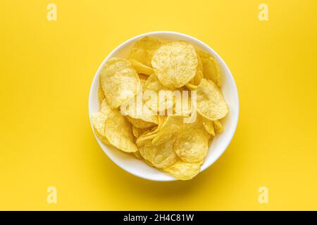 Crunchy potato chips. Potato crisps on yellow background. Top view. Stock Photo