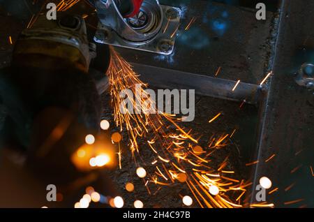 Industrial worker using angle grinder cutting metal. Worker working with angle grinder and has orange sparks. Tool for cut and grinding steel. Safety Stock Photo