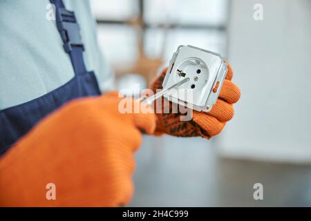 Male electrician hands fixing electrical wall socket Stock Photo