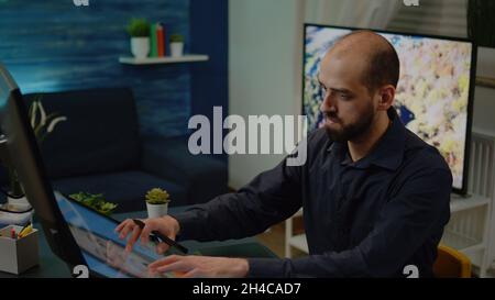 Man photographer retouching photo with graphic tablet and stylus in artwork space. Image designer working with editing software on touch screen computer at studio. Photography editor Stock Photo
