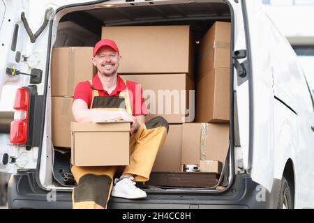 Man courier holding a parcel while sitting in the truck Stock Photo