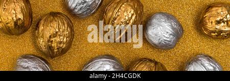 Painted golden and silver walnuts on glittering background Stock Photo