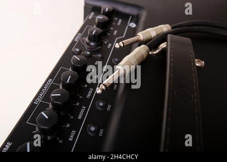 Black electric amplifier with cable on white background. Stock Photo