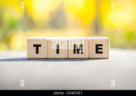 Word TIME made of wooden alphabet blocks outdoors. Autumn season concept. Stock Photo