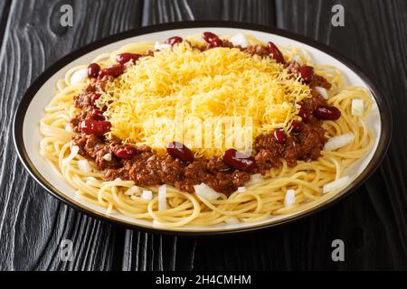Delicious Cincinnati chili with spaghetti, cheddar cheese, fresh onions and beans close-up in a plate on the table. horizontal Stock Photo