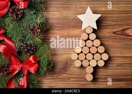 Christmas tree from wine corks with a star on top on a wooden background with fir branches, cones and bows Stock Photo