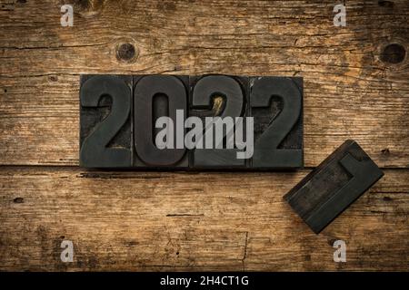 Turn of the year 2021 to 2022 written with vintage letterpress printing blocks on rustic wooden background Stock Photo