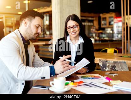 Young colleagues working on new plans and ideas manking calculations at nice modern cafe Stock Photo