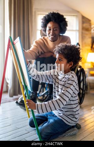 Happy woman with disability learning together with a child. People education fun concept Stock Photo