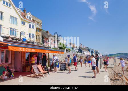 People queueing for Ice cream at an Ice cream kiosk cafe on Marine Parade seafront overlooking sandy beach at Lyme Regis Dorset England UK GB Europe Stock Photo