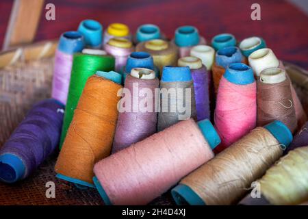 A basket of cotton thread spools of various colors in a Chinese tailor shop Stock Photo