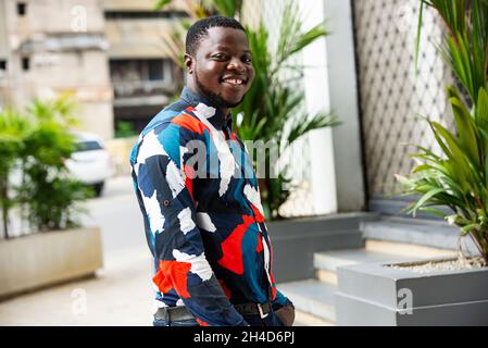 handsome young man standing outdoors in the street posing and looking at camera smiling Stock Photo