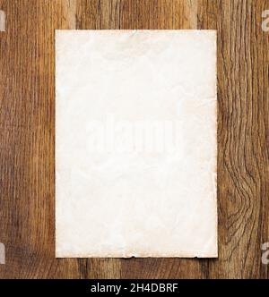 Vintage background graphic design element. Sheet of old parchment paper on a dark wood desk. Ideal for a website template or border Stock Photo