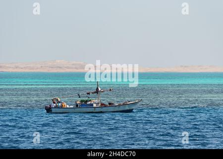 Small white motor fishing boat with fishermen on board for fishery in the Red sea, Egypt Stock Photo