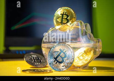 Bitcoin background, cryptocurrency virtual currency market concept. Gold silver bitcoin coins with piggy bank on the background of a laptop with an ex Stock Photo